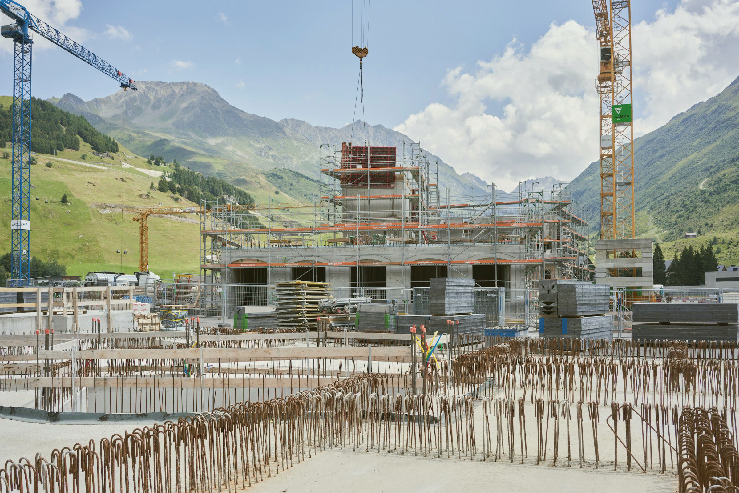 A residential building rising under tower cranes